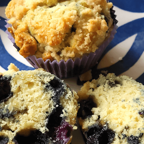 blueberry muffin on a plate with another muffin cut in half