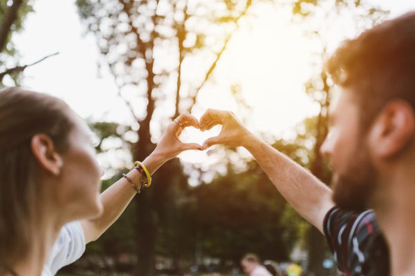 couple outside making a heart